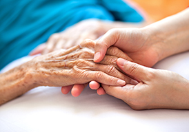 Close up of a younger person's hands holding older person's hands