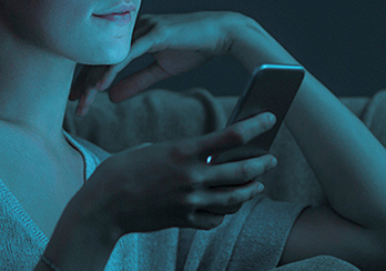 Man sitting at a table holding and looking at a cell phone