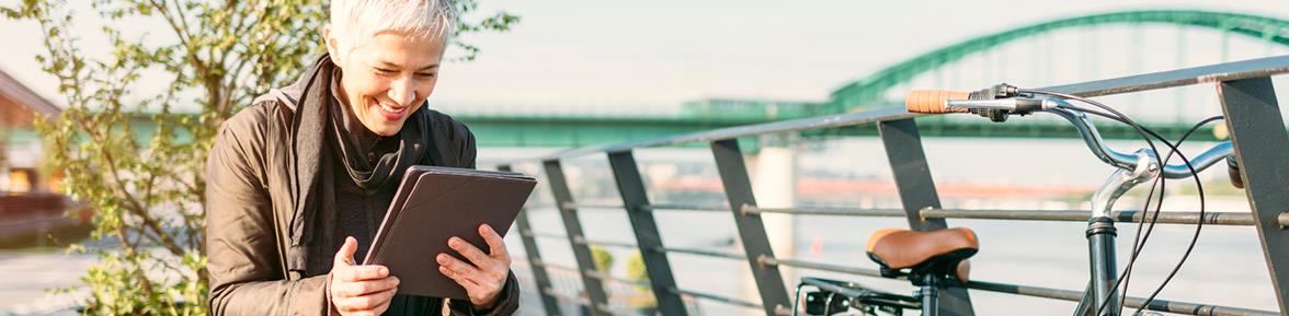 Woman outdoors sitting on bench looking at iPad