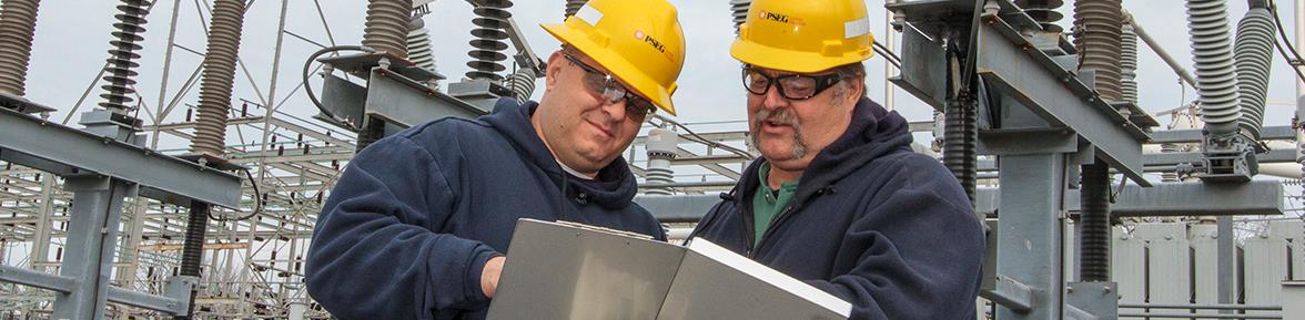 Two men in hard hats looking at plans