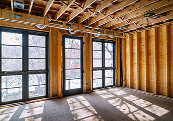 Interior of partially constructed room with windows in place and ceiling beams visible