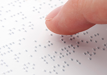 A finger hovering over a document written in Braille