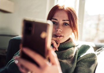 Man wearing a phone headset; woman wearing a similar headset in the background