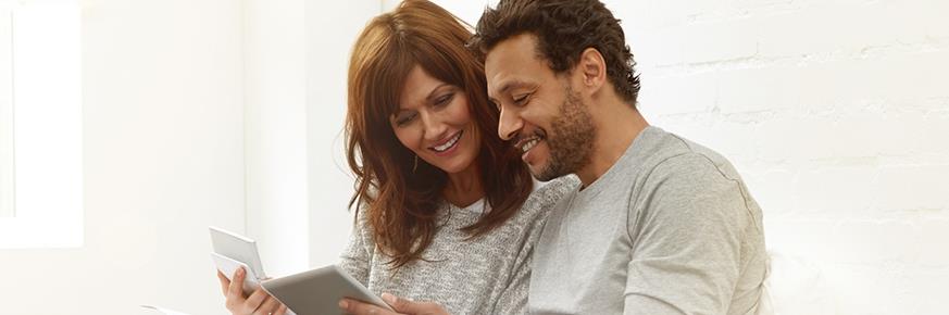 A couple looking at a tablet and a piece of paper