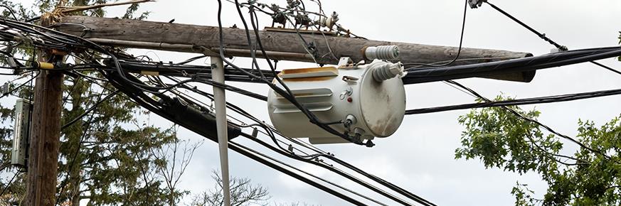Snapped utility pole and transformer lying across wires