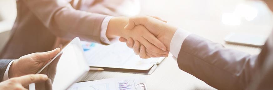 Handshake over a table with papers on it