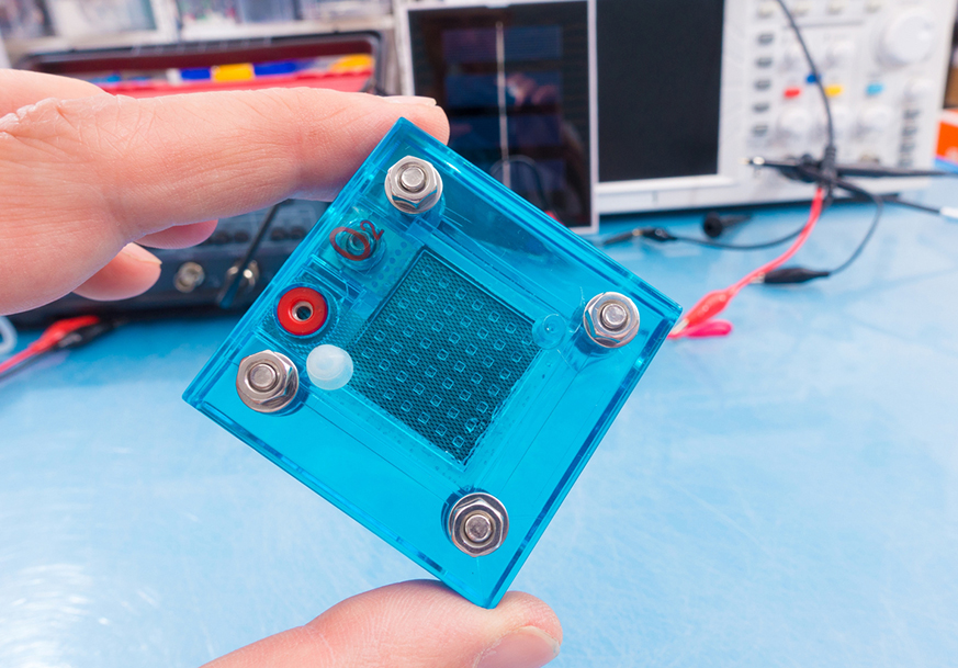 Fingers holding a blue fuel cell