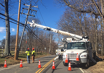 Crews and a bucket truck repairing a utility pole