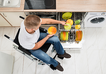  Man in wheelchair unloading a dishwasher