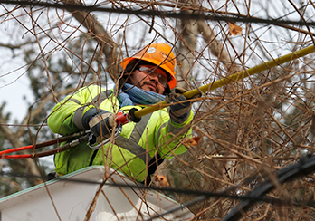 A utility worker in a bucket lift repairing wires