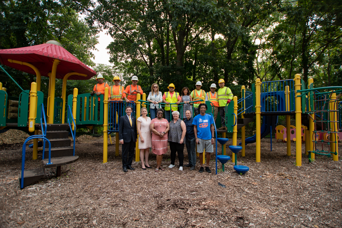 North Hempstead Councilwoman Veronica Lurvey (bottom row, second from l.) joined Manhasset Great Neck EOC staff and PSEG Long Island' employees and tree trim contractors to celebrate PSEG Long Island removing a hazard tree from the nonprofit's property and donating the chips for use in the children's playground.