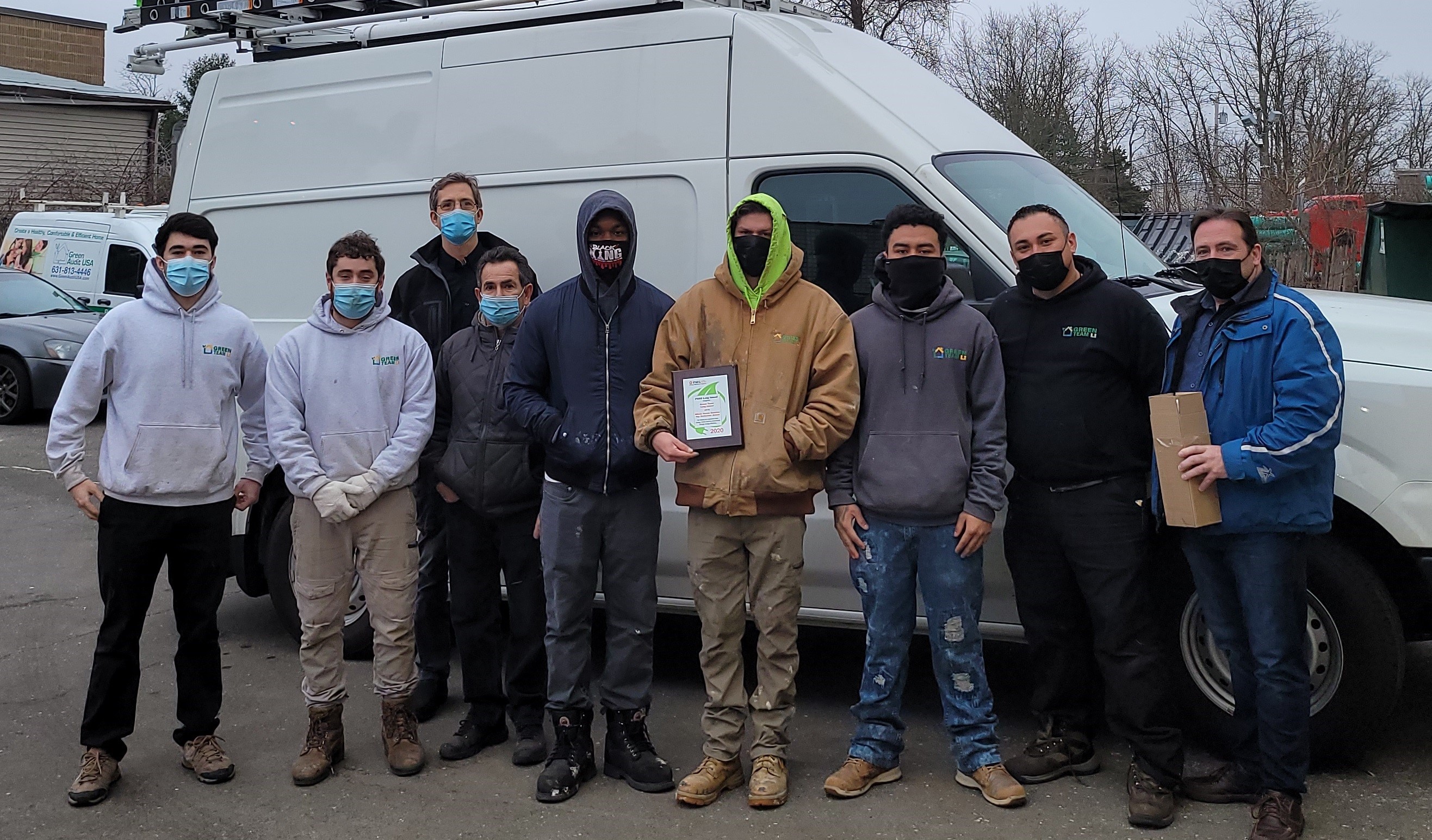Employees of Green Team LI stand together in masks outside a van.