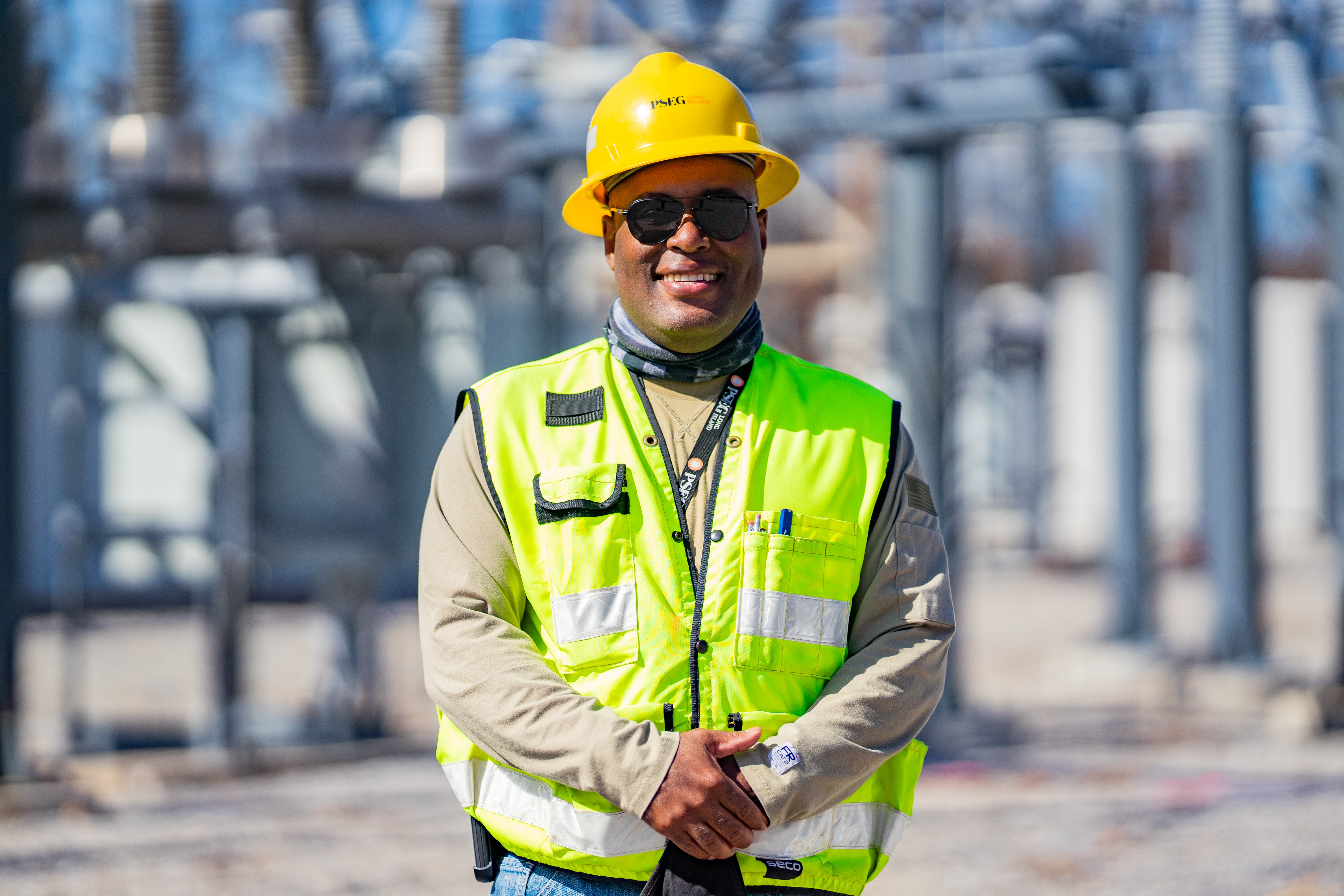PSEG Long Island Surveyor Terry Small smiles for the camera wearing a hard hat and reflective vest.